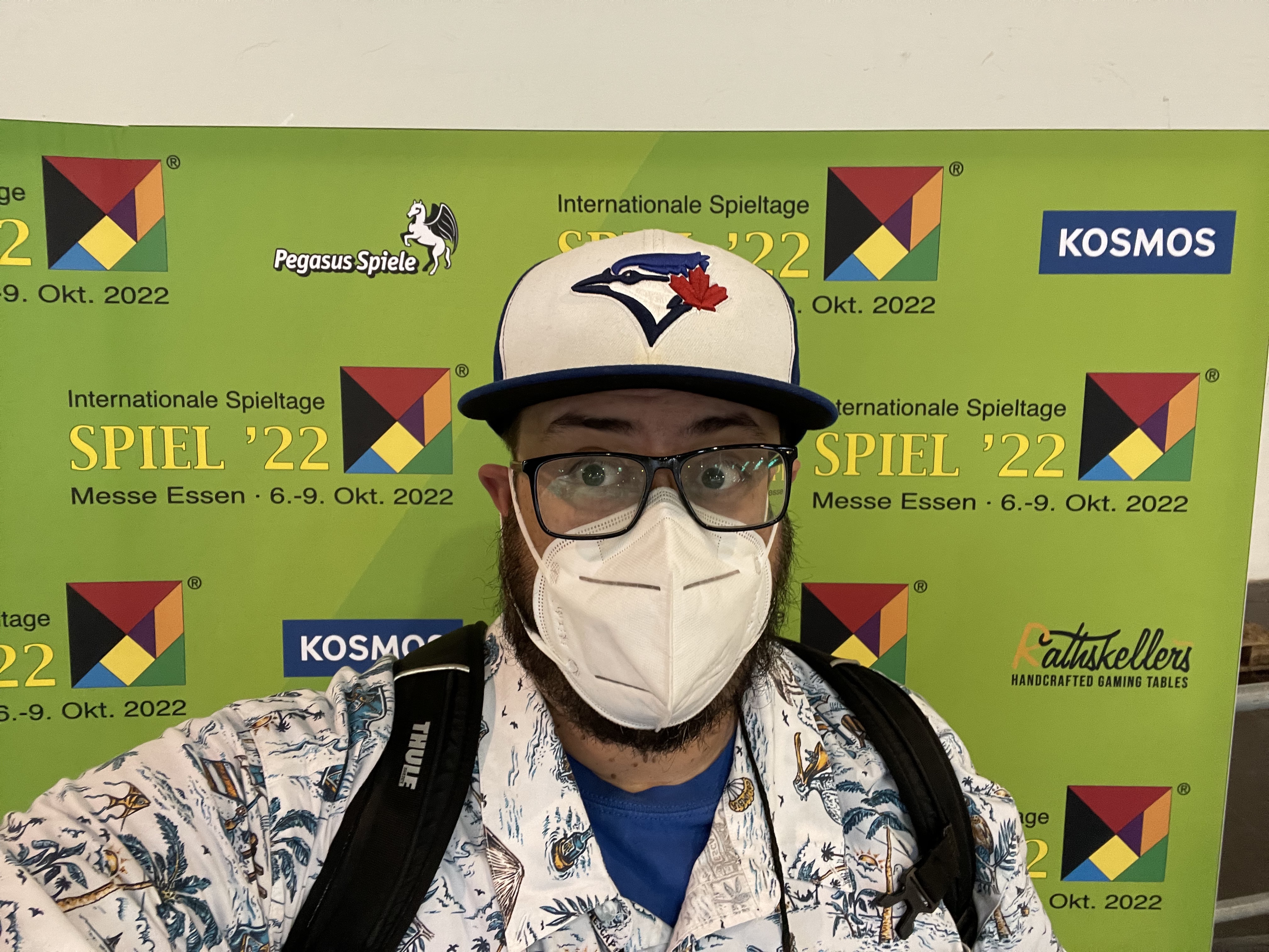 A masked Daryl Andrews in front of a photo backdrop at Essen 2022