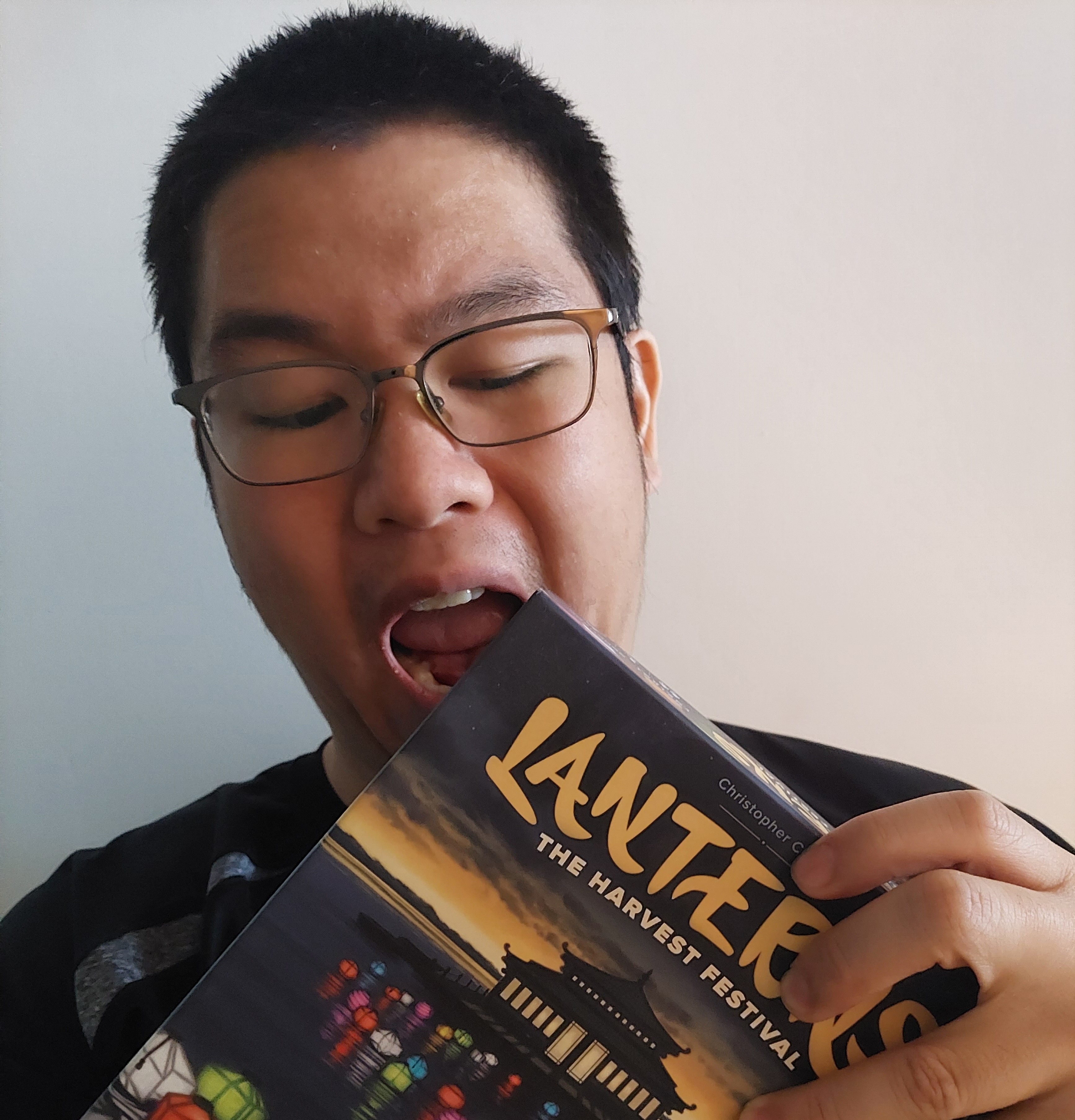 Christopher holding a copy of his game lanterns and pretending to take a bite