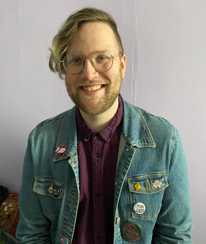 Will wearing a stylish green jean jacket while smiling at the camera