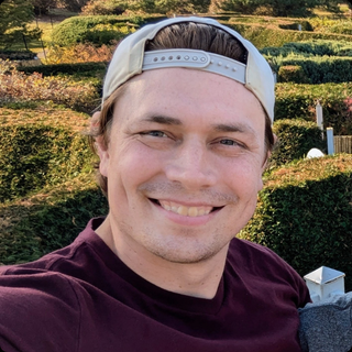 Headshot of Asa Donald wearing a backwards ball cap. 