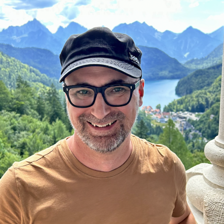 Headshot of Derek Gour with a mountain landscape in the background