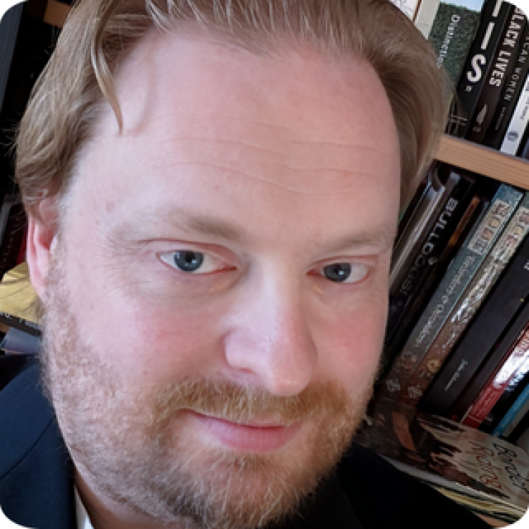 Jason Pitre in front of a bookshelf. 